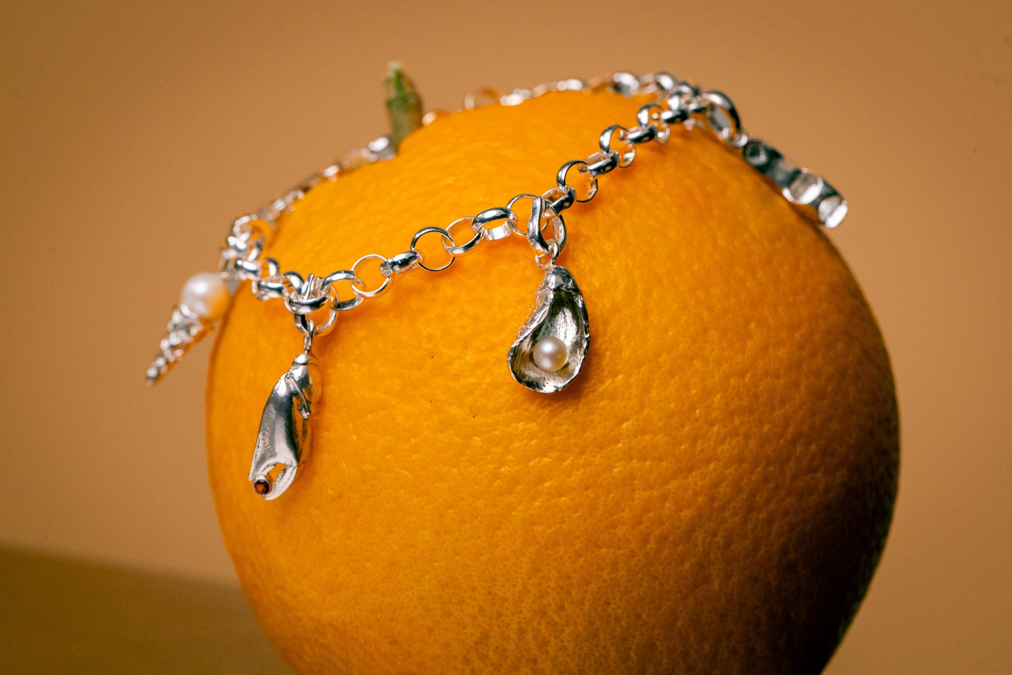 Bedelarmband met bedels, oester, krabbenpoot met edelsteentje en ijshoorn met parel