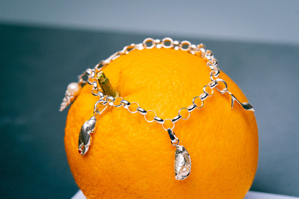 Close up van anker bedelarmband met verschillende bedels met parels en edelstenen 