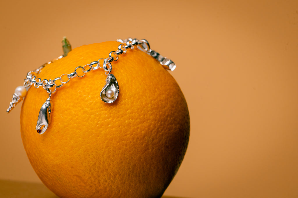 Close-up van bedelarmband met verschillende bedels met parels en edelstenen
