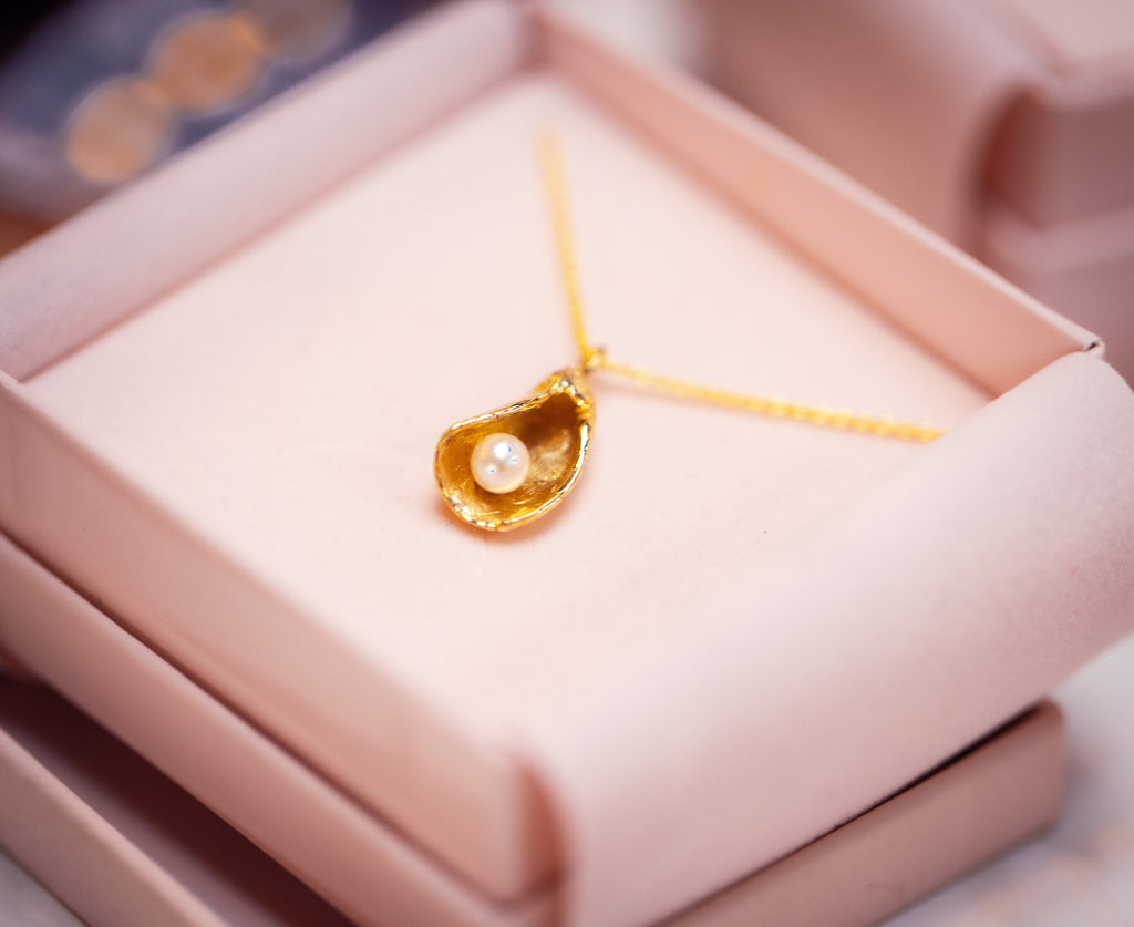 Close up van gouden collier met oester en parel in doosje - Lara Boulangerie 