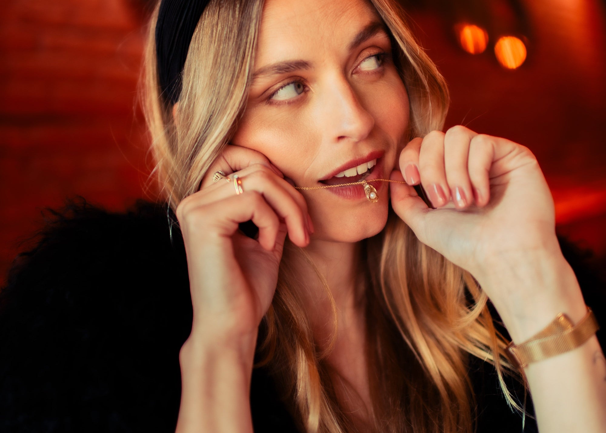 Model met La Perle D'Huître collier bij lippen. Gouden parelsieraad. Lara Boulangerie 