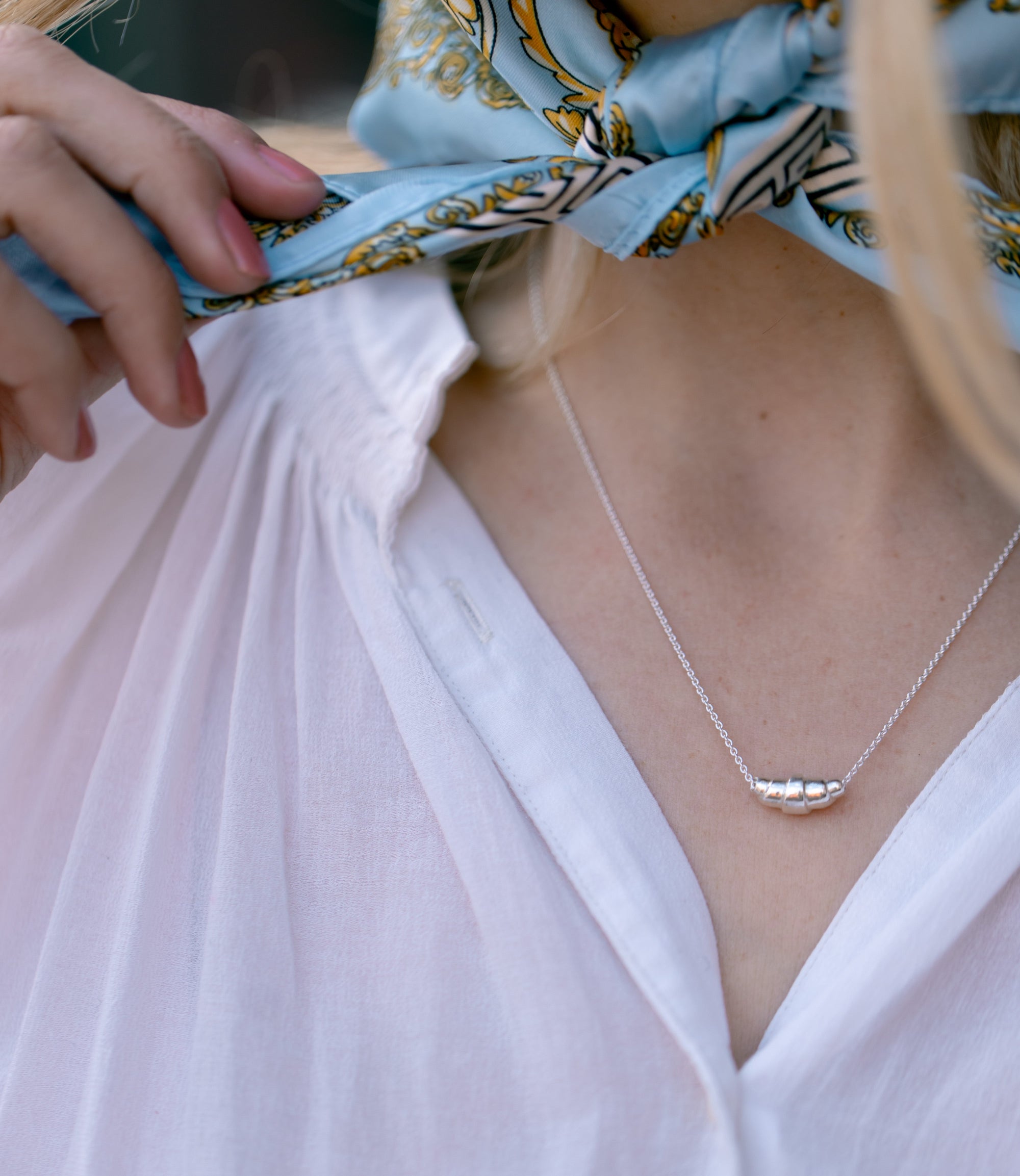 Woman wearing silver croissant pendant necklace - Lara Boulangerie